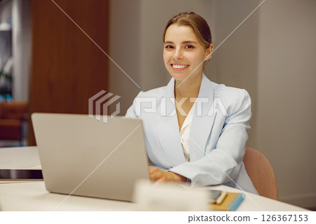 A dedicated professional woman is working on her laptop in a modern office, showcasing expertise 126367153