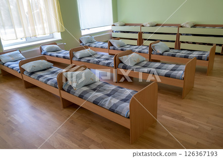 Many small beds in daycare preeschool empty bedroom. 126367193