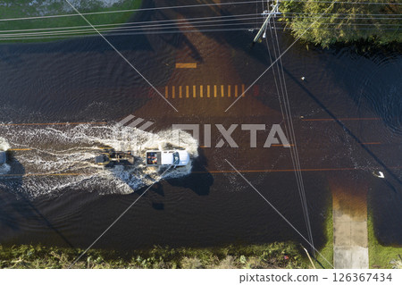 Hurricahe fainfall flooded Florida road with evacuating cars and surrounded with water houses in suburban residential area Hurricahe fainfall flooded Florida road with evacuating cars and surrounded with water houses in suburban residential area 126367434
