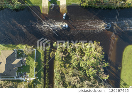 Hurricahe fainfall flooded Florida road with evacuating cars and surrounded with water houses in suburban residential area Hurricahe fainfall flooded Florida road with evacuating cars and surrounded with water houses in suburban residential area 126367435