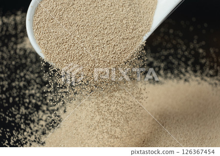 Dry yeast is poured out of a spoon Dry yeast is poured out of a spoon 126367454