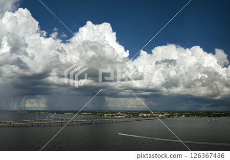 Heavy thunderstorm approaching traffic bridge connecting Punta Gorda and Port Charlotte over Peace River. Bad weather conditions for driving during rainy season in Florida 126367486