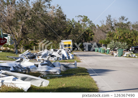 Heaps of debris rubbish on street side near severely damaged by hurricane houses in Florida mobile home residential area. Consequences of natural disaster 126367490