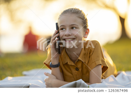 Happy pretty child girl talking on her cellphone in summer park 126367496
