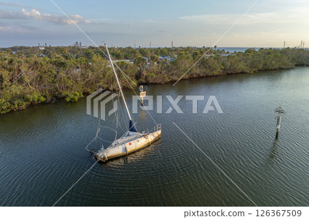Half sunken sailing yacht capsized on shallow bay waters after hurricane Ian in Manasota, Florida Half sunken sailing yacht capsized on shallow bay waters after hurricane Ian in Manasota, Florida 126367509