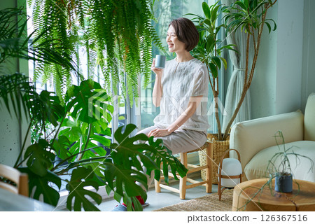 A woman relaxing surrounded by foliage plants 126367516