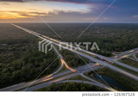 Freeway overpass junction in Florida with fast moving traffic cars and trucks in American rural area at sunset. Interstate transportation infrastructure in USA 126367528