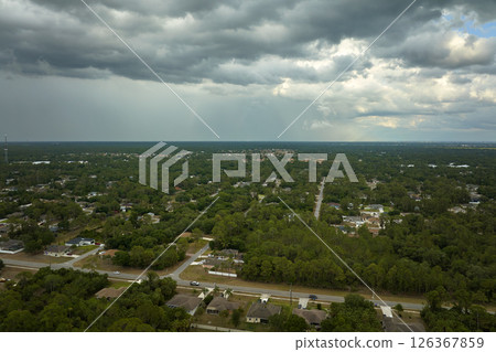 Dark stormy clouds forming on gloomy sky before heavy rainfall over suburban town area Dark stormy clouds forming on gloomy sky before heavy rainfall over suburban town area 126367859