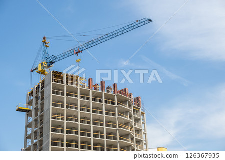 Concrete frame of tall apartment building under construction and tower crane in a city. Concrete frame of tall apartment building under construction and tower crane in a city. 126367935