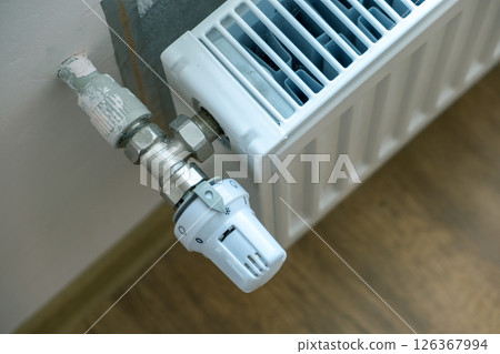 Closeup of heating radiator valve for comfortable temperature regulation on metal radiator on inrerior wall. 126367994