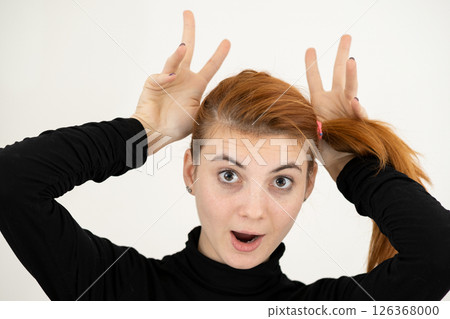 Close up portrait of funny girl holding her ears with hands like a monkey. Close up portrait of funny girl holding her ears with hands like a monkey. 126368000