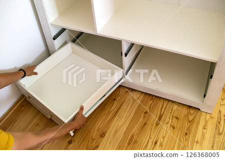 Close up of installation of wooden drawer in contemporary cupboard cabinet. 126368005