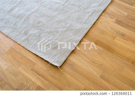 Close up of crumpled carpet laying on parquet wooden floor. Close up of crumpled carpet laying on parquet wooden floor. 126368011
