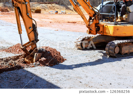 Heavy machinery is digging into ground at construction site during works construction area 126368256
