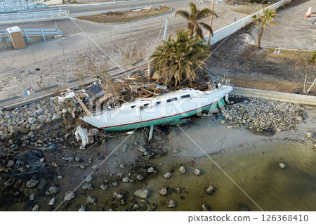 Capsized sunken sailing boat left forsaken on shallow bay waters after hurricane Milton in Englewood, Florida 126368410