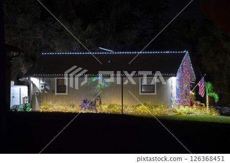 Brightly illuminated christmas decorations on front yard of florida family home. Outside decor for winter holidays 126368451