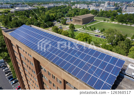 Apartment building with solar roof. Blue photovoltaic panels for producing clean ecological electric energy. Investing in renewable electricity concept Apartment building with solar roof. Blue photovoltaic panels for producing clean ecological electric energy. Investing in renewable electricity concept 126368517