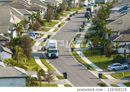 American garbage truck picking up trash bins on rural street side 126368526