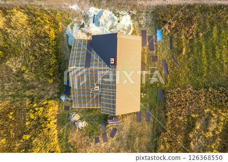 Aerial view of unfinished house with wooden roof structure covered with metal tile sheets under construction. 126368550
