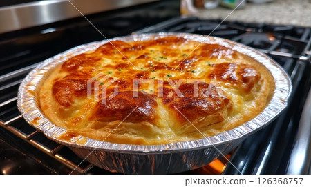 Golden-brown homemade pot pie with flaky crust baking in oven. Golden-brown homemade pot pie with flaky crust baking in oven. 126368757