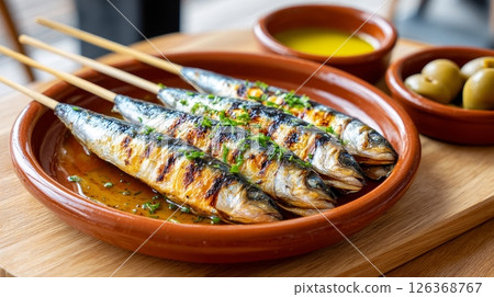 Grilled sardines on clay plate with olives and olive oil dressing. 126368767