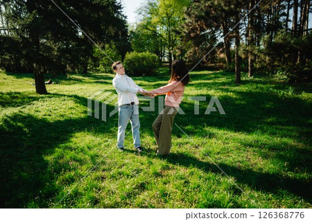 Joyful couple dancing in a sunny park during a warm spring afternoon 126368776