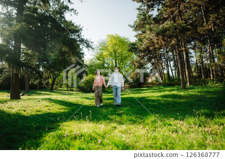 Two friends enjoying a peaceful walk through a lush green park in spring 126368777