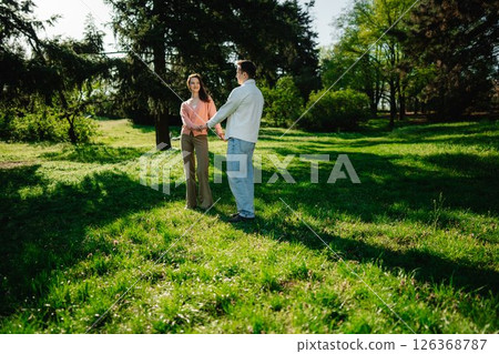 Couple enjoys a joyful moment together in a sunny green park Couple enjoys a joyful moment together in a sunny green park 126368787