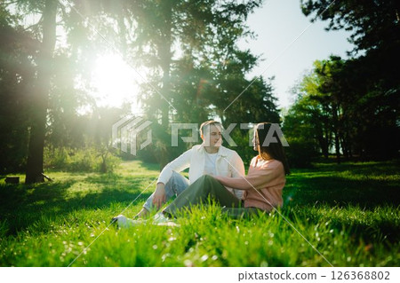 Couple enjoys a serene afternoon together in a sunlit forest clearing 126368802
