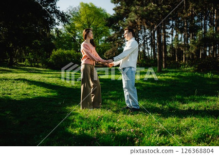 Couple enjoys a romantic moment in a sunlit park during springtime Couple enjoys a romantic moment in a sunlit park during springtime 126368804