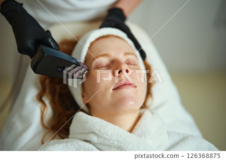 Woman receiving facial treatment in a wellness salon during daylight hours 126368875