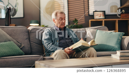 Senior man, reading book and relax on sofa with study, literature and information in lounge at apartment. Elderly person, novel and knowledge on couch with language for storytelling in living room Senior man, reading book and relax on sofa with study, literature and information in lounge at apartment. Elderly person, novel and knowledge on couch with language for storytelling in living room 126368895