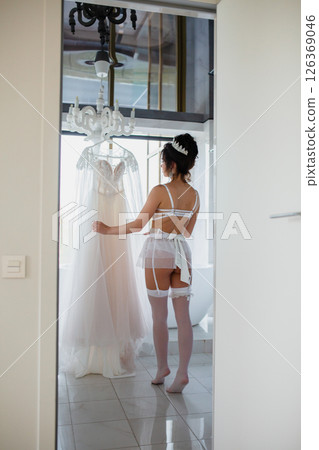 Seductive bride in a sexy lingerie and white stockings posing in a bathroom near her bridal dress 126369046