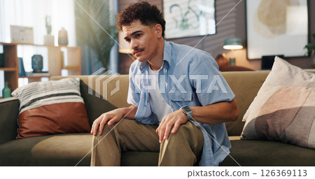 Sad, home and man on sofa, thinking and thoughtful with depression in living room. Apartment, anxiety and person on couch, tired and contemplation with regret, mental health and memory with stress 126369113