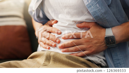 Stomachache, hands and person in home, pain and man with food poisoning in living room or indigestion. Abdominal, cramps and discomfort on couch, gas and bloating in lounge, diarrhea or constipation Stomachache, hands and person in home, pain and man with food poisoning in living room or indigestion. Abdominal, cramps and discomfort on couch, gas and bloating in lounge, diarrhea or constipation 126369333