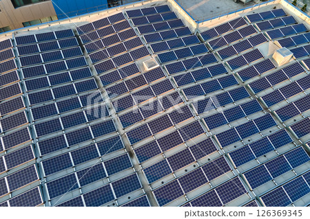 Aerial view of solar power plant with blue photovoltaic panels mounted on industrial building roof for producing green ecological electricity. Production of sustainable energy concept Aerial view of solar power plant with blue photovoltaic panels mounted on industrial building roof for producing green ecological electricity. Production of sustainable energy concept 126369345