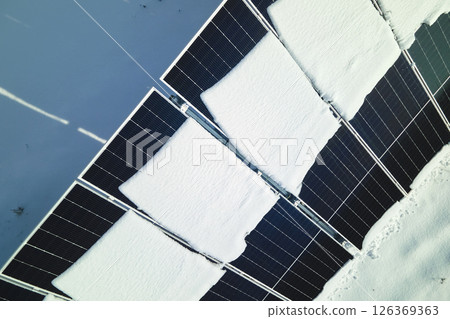Aerial view of snow melting from covered solar photovoltaic panels at sustainable electric power plant for producing clean electrical energy. Low effectivity of renewable electricity in winter Aerial view of snow melting from covered solar photovoltaic panels at sustainable electric power plant for producing clean electrical energy. Low effectivity of renewable electricity in winter 126369363