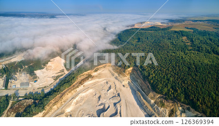 Aerial view of open pit mining of limestone materials for construction industry with excavators and dump trucks. 126369394