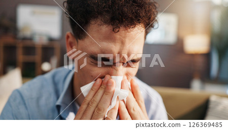 Sick man, sofa and blowing nose with tissue for flu, cold or hayfever season at home. Male person, influenza and sinus with sneeze, allergy or viral infection for virus, bacteria or germs at house 126369485
