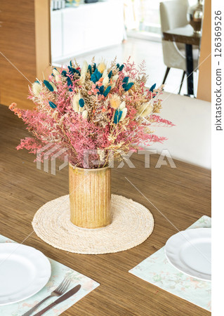 Plate and utensils, on the table decorated with a small flower arrangement Plate and utensils, on the table decorated with a small flower arrangement 126369526