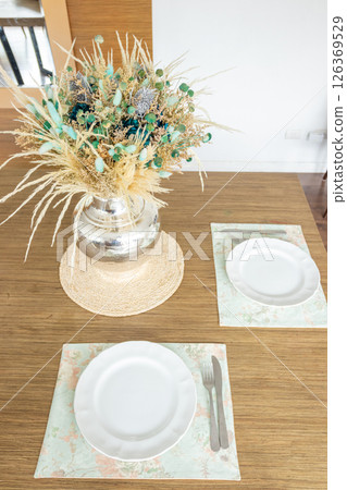 Plate and utensils, on the table decorated with a small flower arrangement Plate and utensils, on the table decorated with a small flower arrangement 126369529