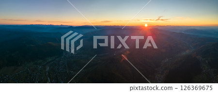 Aerial view of dark mountain hills with bright sunrays of setting sun at sunset. Hazy peaks and misty valleys in evening 126369675