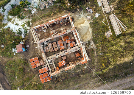 Aerial view of building site for future brick house, concrete foundation floor and stacks of yellow clay bricks for construction. Aerial view of building site for future brick house, concrete foundation floor and stacks of yellow clay bricks for construction. 126369700