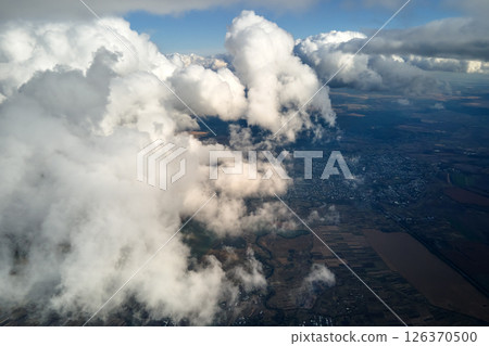 Aerial view from airplane window at high altitude of earth covered with white puffy cumulus clouds 126370500