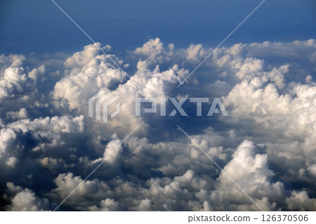 Aerial view from above at high altitude of dense puffy cumulus clouds flying. Amazing from airplane window point of view 126370506