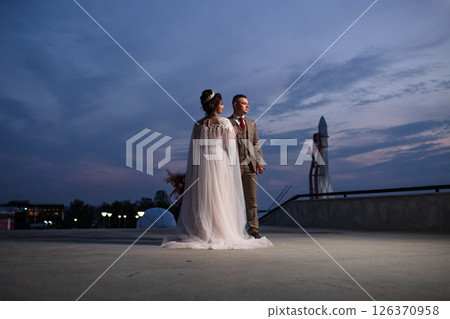 Young beautiful couple of newlywed posing in the evening against the background of an atmospheric panorama and stunning sunset 126370958