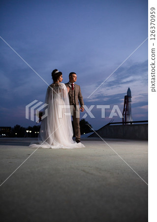 Young beautiful couple of newlywed posing in the evening against the background of an atmospheric panorama and stunning sunset 126370959