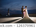 Young beautiful couple of newlywed posing in the evening against the background of an atmospheric panorama and stunning sunset 126370961