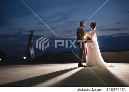 Young beautiful couple of newlywed posing in the evening against the background of an atmospheric panorama and stunning sunset 126370961