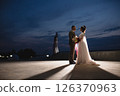 Young beautiful couple of newlywed posing in the evening against the background of an atmospheric panorama and stunning sunset 126370963